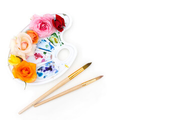 Watercolor palette with multi-colored rosebuds and art brush on a white background. The colors of summer. Creative concept of colorful summer.