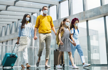 Family with two children going on holiday, wearing face masks at the airport.
