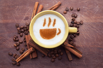 A retro cup with coffee cream. Food art creative concept image, cute drawing with cinnamon powder over milk cream on a wooden background.