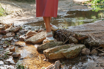 Girl on stones crosses a brook