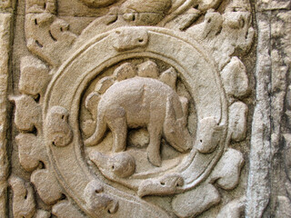 A carved stone figure of a stegosaurus dinosaur on a wall in Ta Prohm temple, Cambodia. © Дмитрий Дмитриев