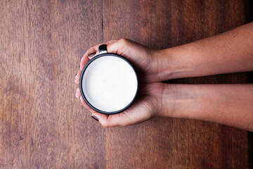 A retro cup with coffee cream. Food art creative concept image, cute drawing with cinnamon powder over milk cream on a wooden background.