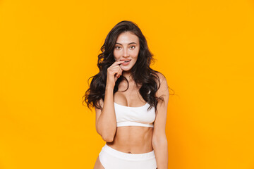 Image of young pleased woman in swimsuit posing and smiling at camera