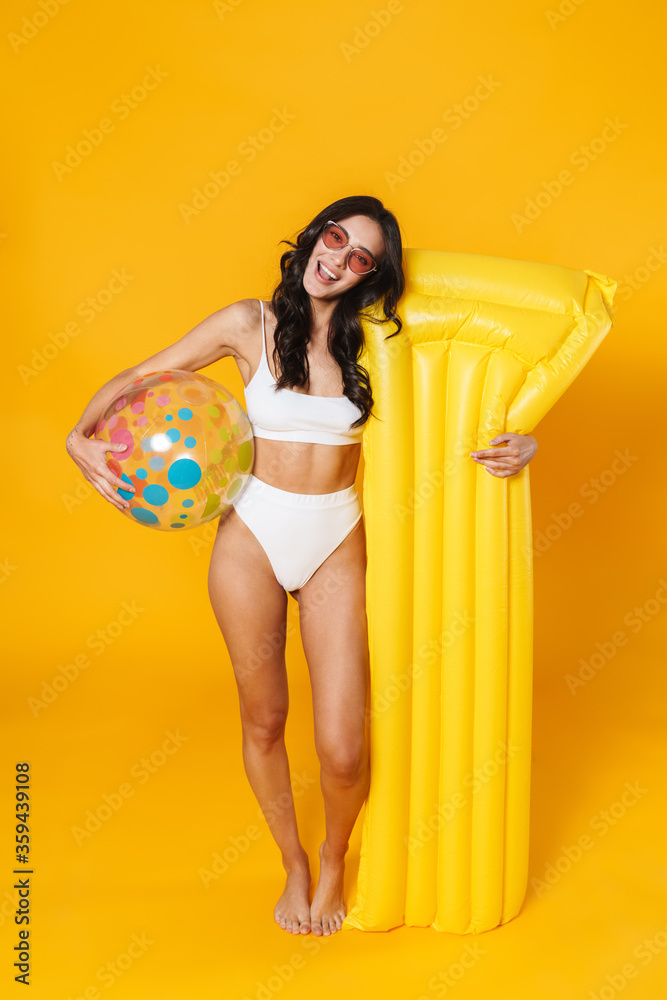 Poster Image of delighted woman in swimsuit posing with ball and air mattress