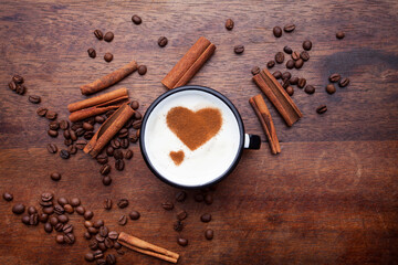 A retro cup with coffee cream. Food art creative concept image, cute drawing with cinnamon powder over milk cream on a wooden background.