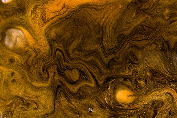 Black and gold mixed inks ripples background.