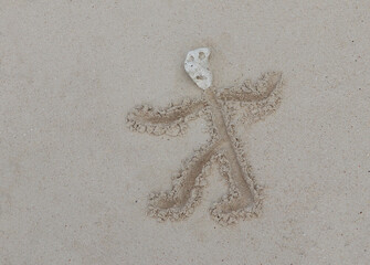 Little man drawn in the sand with a head from a piece of coral