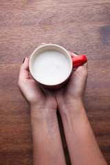 A retro cup with coffee cream. Food art creative concept image, cute drawing with cinnamon powder over milk cream on a wooden background.