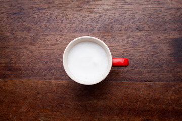 A retro cup with coffee cream. Food art creative concept image, cute drawing with cinnamon powder over milk cream on a wooden background.