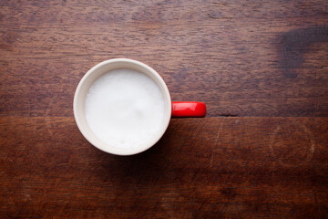 A retro cup with coffee cream. Food art creative concept image, cute drawing with cinnamon powder over milk cream on a wooden background.