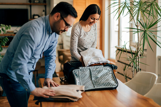 Portrait of a couple packing clothes for travel, at home.