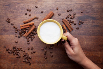 A rustic mug with coffee cream. Food art creative concept image, drawing with cinnamon powder over wooden background.
