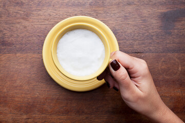 A rustic mug with coffee cream. Food art creative concept image, drawing with cinnamon powder over wooden background.
