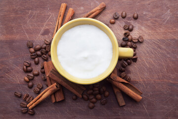 A rustic mug with coffee cream. Food art creative concept image, drawing with cinnamon powder over wooden background.