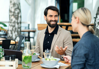 Happy couple sitting outdoors on terrace restaurant, talking.