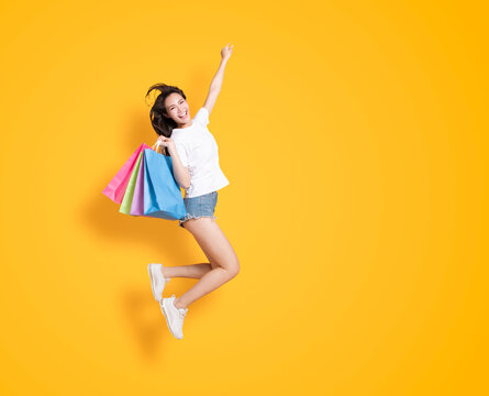 happy young woman holding with shopping bags and jumping