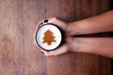 A rustic mug with coffee cream. Food art creative concept image, drawing with cinnamon powder over wooden background.