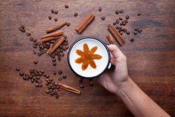 A rustic mug with coffee cream. Food art creative concept image, drawing with cinnamon powder over wooden background.