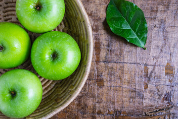 Green apple in a basket on a wooden table