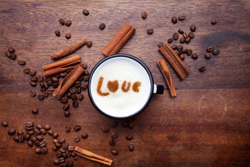 A rustic mug with coffee cream. Food art creative concept image, drawing with cinnamon powder over wooden background.