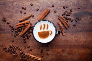 A rustic mug with coffee cream. Food art creative concept image, drawing with cinnamon powder over wooden background.