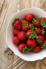 Vertical image of strawberries in a white rustic bowl.
