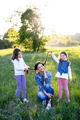 Mother with two small daughters having fun outdoors in spring nature.