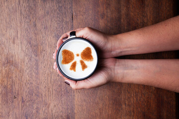A rustic mug with coffee cream. Food art creative concept image, drawing with cinnamon powder over wooden background.
