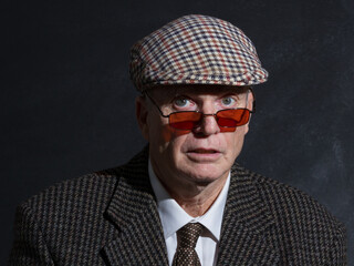 English gentleman in tweed jacket and tweed flat cap poses for portrait