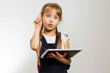 The little girl using the tablet on the white wall background