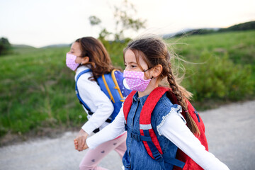 Two small girls on trip outdoors in nature, wearing face masks.