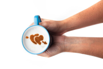 A rustic mug with coffee cream. Food art creative concept image, drawing with cinnamon powder over cream in a white background.
