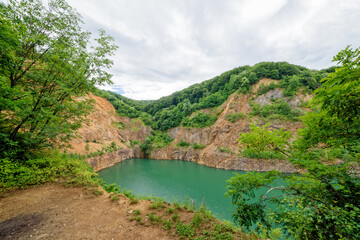 Fototapeta na wymiar Beautiful Lake Ledinci (serbian: Ledinacko jezero) near Fruska Gora in Serbia, once there was a stone pit. Beautiful vibrant green deep mountain lake, hidden and surrounded by rocks and woods.