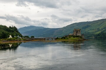 Landscape of Eilean Donan Castle, Scotland reflected in waters of Loch Duich in typical Scottish cloudy weather