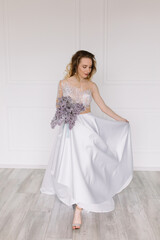 Fototapeta premium Beautiful girl woman bride in a delightful wedding dress with a bouquet of flowers dancing in front of a mirror portrait of a blonde with blue eyes holding