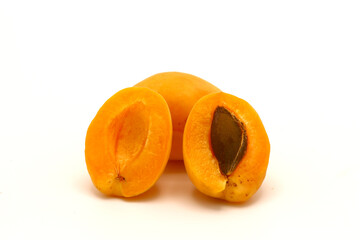 Two ripe apricots on a light background. One whole. One cutaway with a drupe. Natural fruits. Close-up.