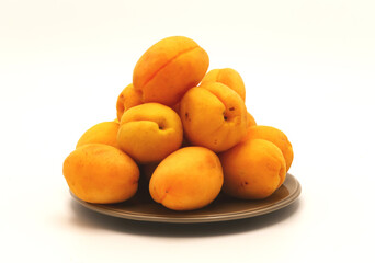 Few ripe apricot lie on a plate on a light background. Natural fruits. Close-up.