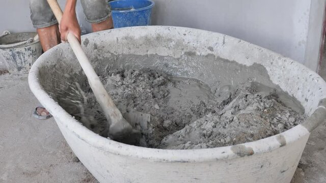 worker mixing concrete in basin