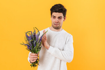 Photo of handsome unhappy man with allergy posing with flowers