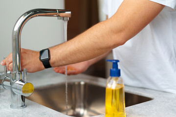 Man washing hands with soap in a sink at his home