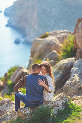 Naklejka na ściany i meble Young couple in love outdoor.Stunning sensual outdoor portrait of young stylish fashion couple posing on the background of mountains and sea