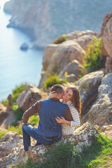 Fototapeta premium Young couple in love outdoor.Stunning sensual outdoor portrait of young stylish fashion couple posing on the background of mountains and sea