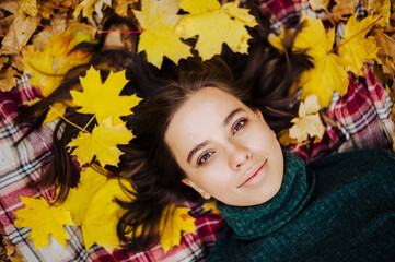 Beautiful girl lies in the yellow autumn leaves. autumn photography. girl and lots of orange leaves