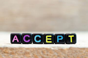Black bead with color letter in word accept on wood background
