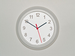 eine Wanduhr auf grauem Hintergrund zeigt die Zeit 01:50 Uhr