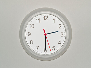 eine Wanduhr auf grauem Hintergrund zeigt die Zeit 02:30 Uhr