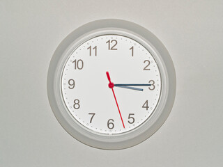 eine Wanduhr auf grauem Hintergrund zeigt die Zeit 03:15 Uhr