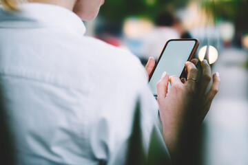 Cropped view of female finger installing application on display of modern smartphone using 4G internet connection.Young woman holding mobile phone in hands and chatting online on cellular device