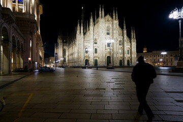Fototapeta na wymiar A man rushing past the Duomo in Milan, Italy