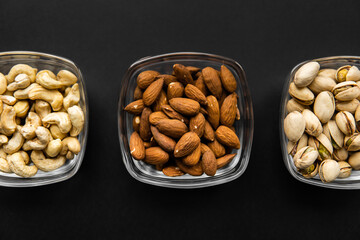 Almond, pistachio and cashew in a small plates which standing on a black table. Nuts is a healthy vegetarian protein and nutritious food.